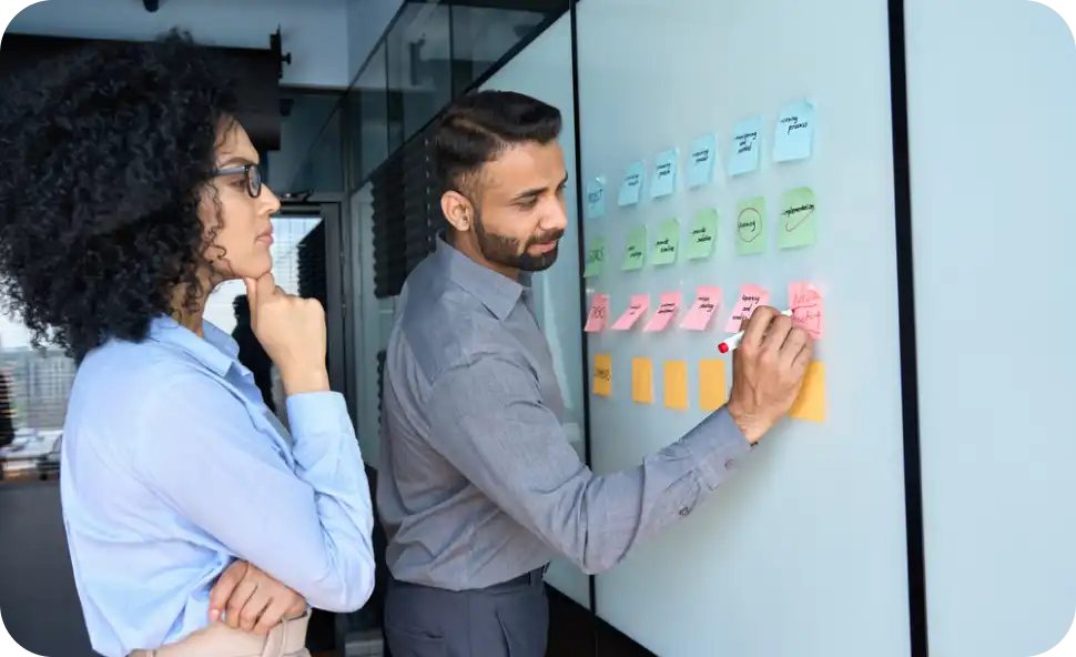 About Us: a man and woman writing on sticky notes on a whiteboard